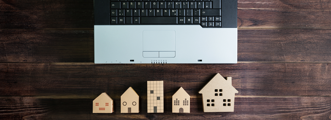 Drewniane modele domów obok laptopa